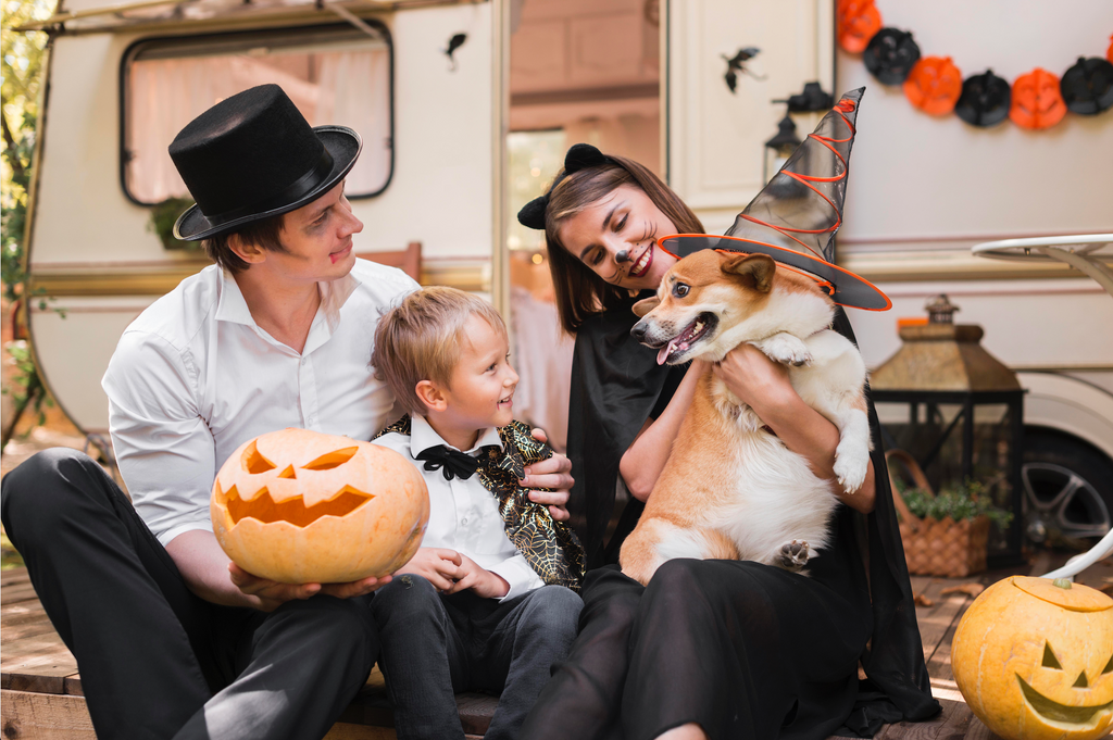 Family in halloween costumes sitting with their corgi, laughing